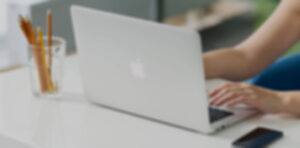 Person using a laptop on a desk with a glass of pencils, illustrating website maintenance and support services by Secure WP Solutions.